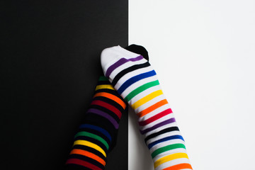 Two embarrassing legs in colorful striped socks on black and white background. Negative pair love concept with two people with different skin color