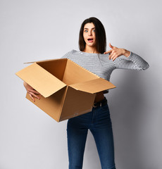 beautiful brunette woman standing on a light background with a moving cardboard box