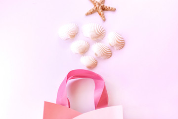Starfish, seashells and gift bag on a delicate pink background. Summer background.