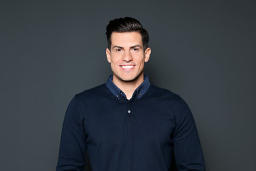 Portrait of handsome man smiling on grey background