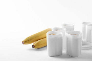 Cups of yogurt with bananas on white background. Multi cooker recipe