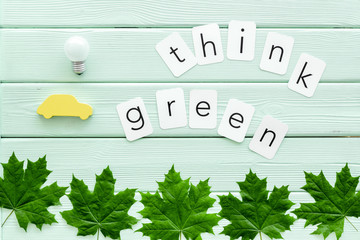 Think green text with car toy, lamp, green maple leaves on mint green wooden background top view