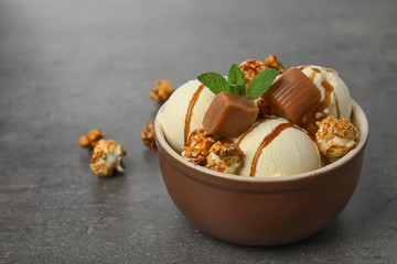 Delicious ice cream with caramel and popcorn in dessert bowl on table. Space for text