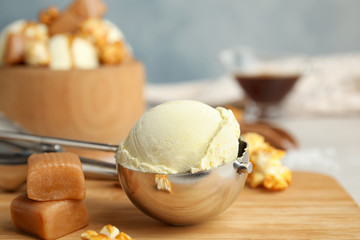 Delicious ice cream in scoop, caramel and popcorn on wooden board