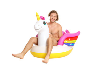 Attractive young man in swimwear with unicorn inflatable ring on white background © New Africa