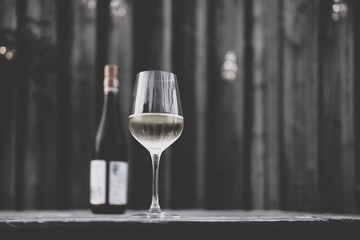 Image of white wine glass with white wine bottle and blurry background