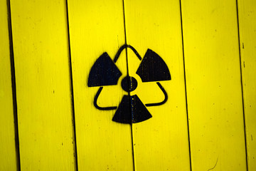 Sign of radiation on a yellow wooden board.