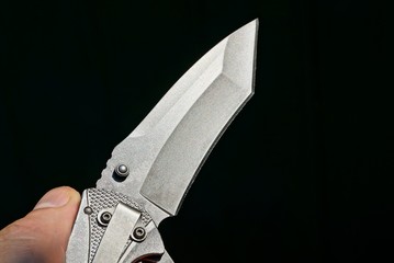 one gray folding knife in hand on a black background