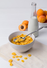 Corn Flakes with apricot at the white wooden table.