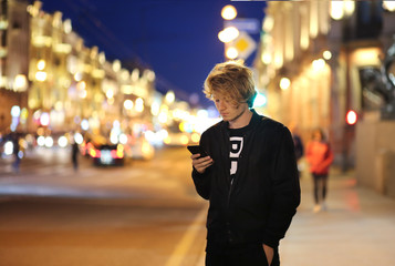 Lifestyle portrait of a teenage boy using a smart phone outdoors