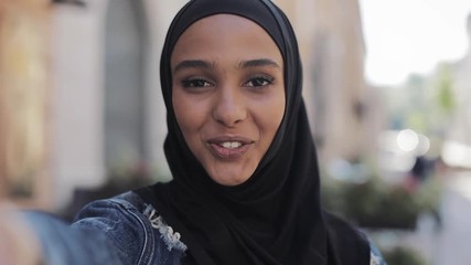 Portrait of young muslim woman wearing hijab having video call using camera while traveling in the beatiful city. - Powered by Adobe