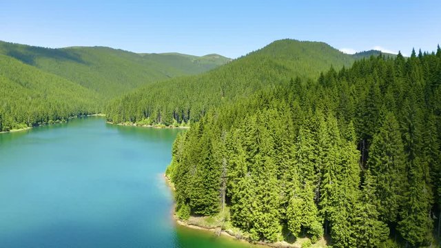 Mountain lake with turquoise water and green trees. Reflection in the water. Beautiful summer landscape with mountains, forest and lake. Aerial View. Drone shot over a beautiful mountain forest lake