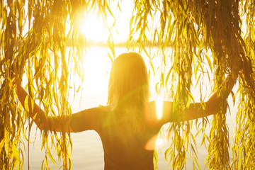 Autumn portrait of young girl with willow branches on the background of a lake at sunset © Sergiy