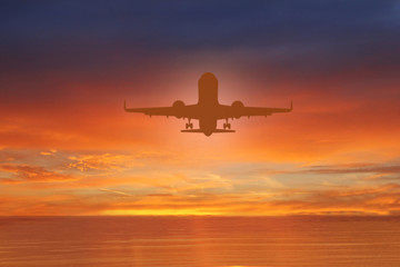 Fototapeta na wymiar Silhouette of plane in the sky above Sea at Sunset. travel, flight, vacation Concept. Low key photo. relax time
