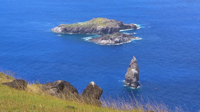 CLOSE UP: Small untouched islet of Motu Nui is surrounded by the vivid blue ocean. Spectacular view of rocky islands near Easter Island. Scenic view of an islet that was used for ancient rituals.