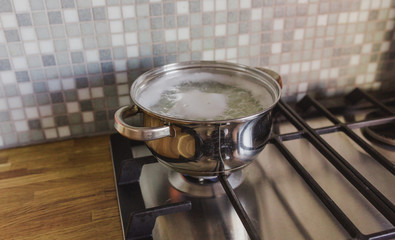 Saucepan on the stove in the kitchen on the background of a wooden tabletop