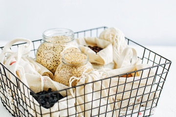 Nuts, dried fruits and  groats  in eco cotton bags and glass jars  in black metal basket. Zero Waste Food Shopping.  Waste-free living