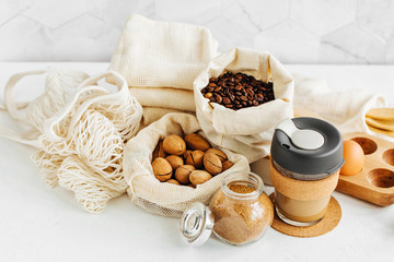 Reusable coffee mug,  produce bags full of nuts and dried fruits.  Glass jars with groats. Zero Waste Food Shopping.  Waste-free living.