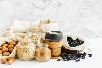 Reusable coffee mug,  produce bags full of nuts and dried fruits.  Glass jars with groats. Zero Waste Food Shopping.  Waste-free living.