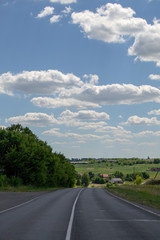 Panorama of the road in the summer evening asphalt road and on the sides of green trees
