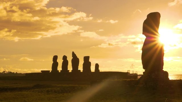 SILHOUETTE, LENS FLARE, COPY SPACE: Scenic view of ancient moai sculptures on the shore of Easter Island on a sunny summer evening. Scenic view of historic archaeological site of Ahu Tahai at sunset.