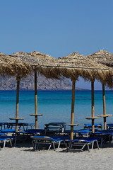 Obraz na płótnie Canvas Beach umbrellas and sun chairs waiting for tourists - Elafonisi beach, Crete