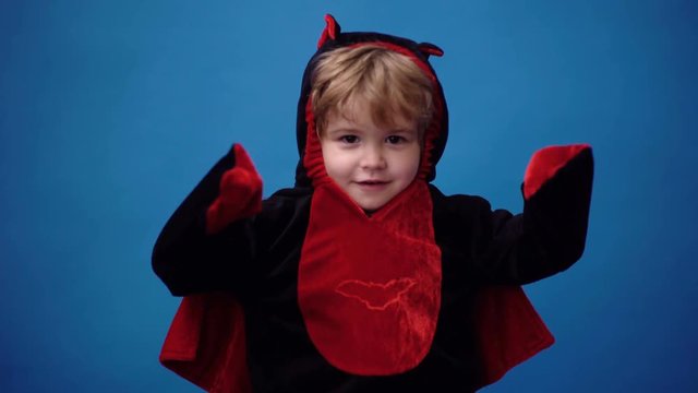Small child boy in black and red suit of dragon. Kid having fun. Surprised boy dressed in fancy dress as dinosaur. Blond boy in dragon costume. Halloween costume. Boy in monster dragon costume.