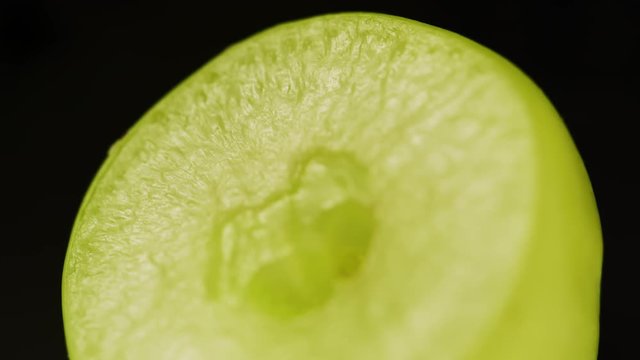 Half of a juicy grape on black background