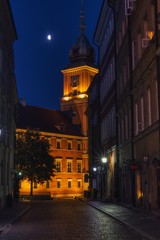 Fototapeta na wymiar nocny widok na ulicę Świętojańską i oświetlony Zamek Królewski, kamienice starówki, oświetlenie księżyca, widoczny zegar na wieży zamkowej