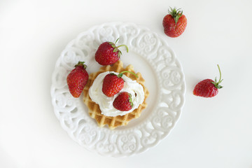 Waffle with Cream and Strawberries in a White Plate isolated on a White Background