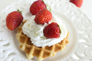 Waffle with Cream and Strawberries in a White Plate isolated on a White Background