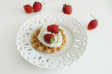 Waffle with Cream and Strawberries in a White Plate isolated on a White Background