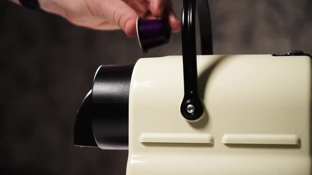 Woman inserting purple capsule in slider of coffee espresso machine