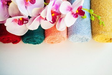 Colored towels and orchid on white table with copy space on bath room background.