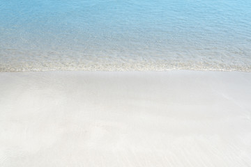Fototapeta na wymiar Soft wave of blue ocean on sandy beach. Summer background.