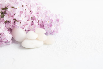 White stones with lilac over white textured background. Spa concept, aromatherapy
