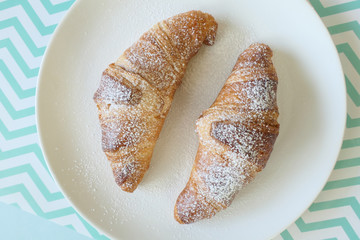 Delicious French Croissants in a White Plate isolated on a Green Zigzag Background