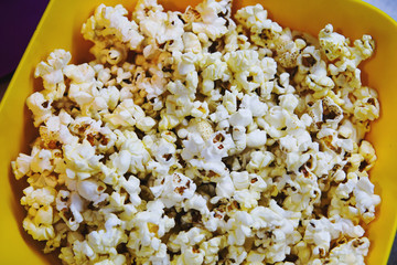Yellow plate with popcorn. Close up, top view.