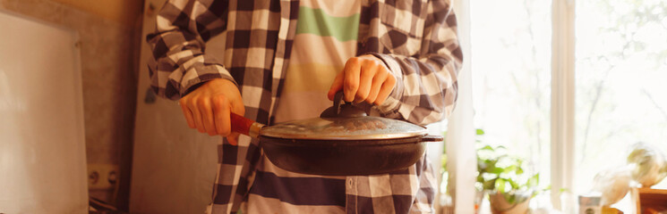 young man cooking healty meal in a pan at the kitchen, food preparation leisures