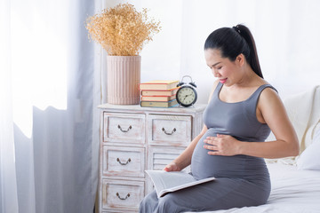 Pregnant woman reading a book in the room.