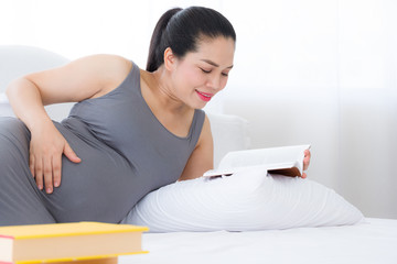Pregnant woman reading a book and put her hand on belly. Mental health care and pregnancy.