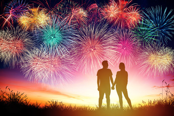 young couple watching fireworks on hill