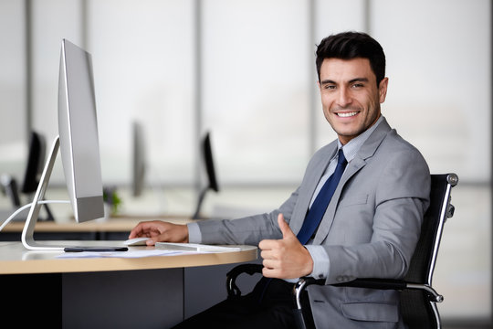 Businessman using computer and thump up..