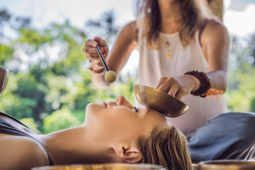 Nepal Buddha copper singing bowl at spa salon. Young beautiful woman doing massage therapy singing...