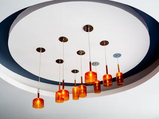Modern orange ceiling lamp hanging from white ceiling. Lighting decoration concept.
