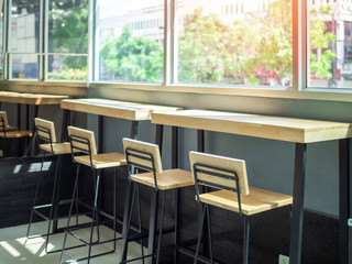 Wooden bar stools and wooden table near the window glass