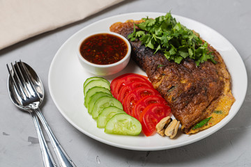 Omelet with mussels. Popular Thai food served with fresh vegetables and sauce on a plate.
