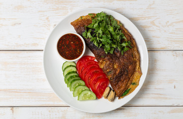 Omelet with mussels. Popular Thai food served with fresh vegetables and sauce on a plate. The view from the top. Copy-space.