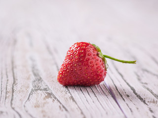 One berry ripe strawberries on a reddish table.