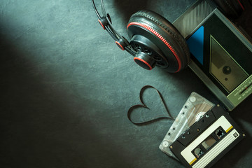 Cassette player and headphone on cement floor. Heart shape of cassette tape strip. Top view and copy space for text. Concept of music is the heart.